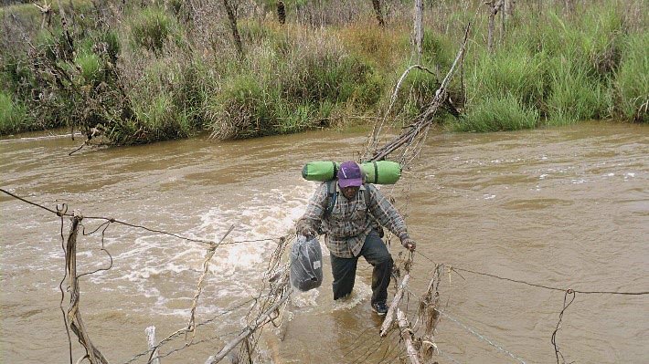 A man walks across a bridge almost entirely submerged in water.