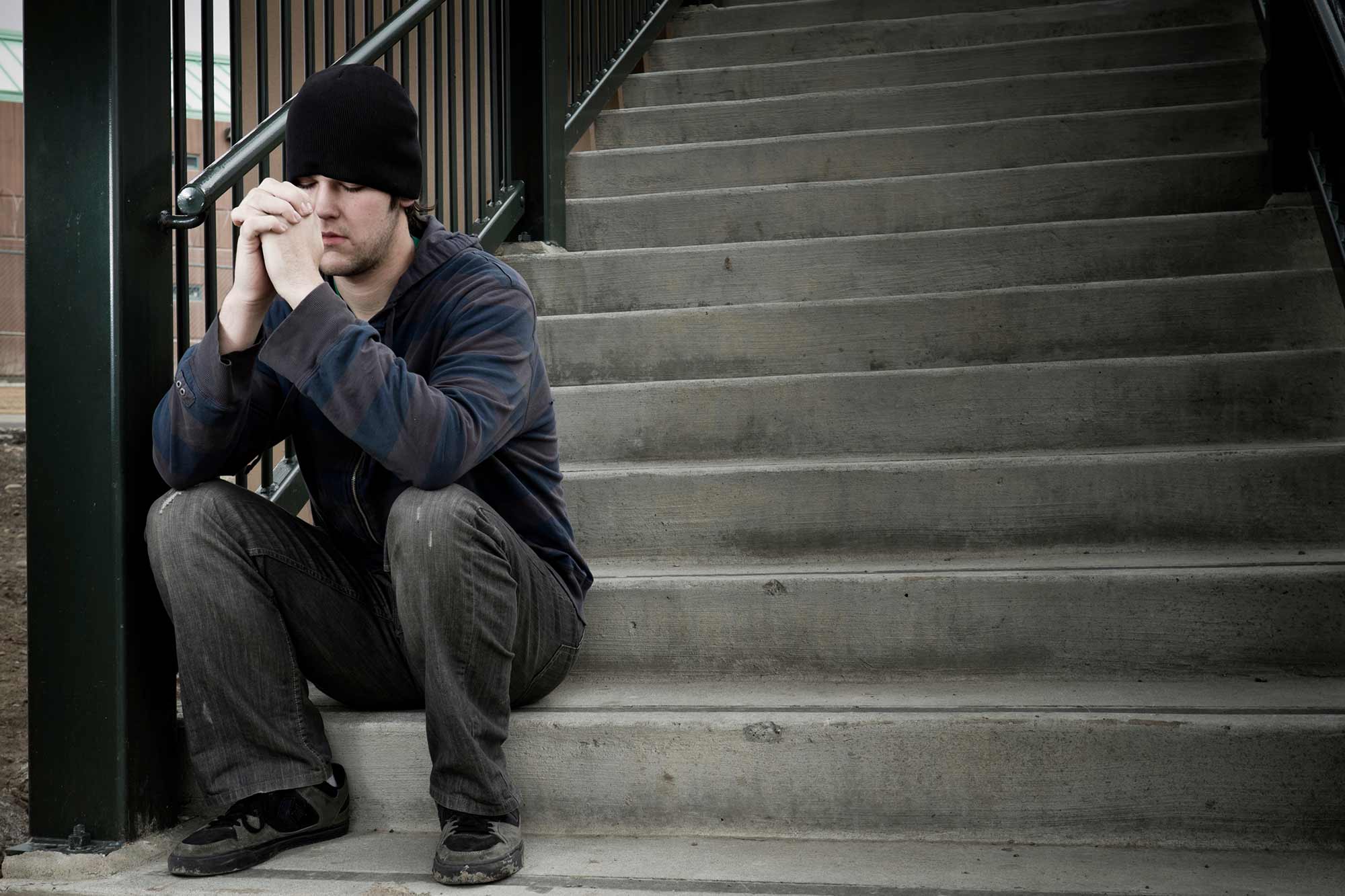 A man sits on a concrete staircase and prays