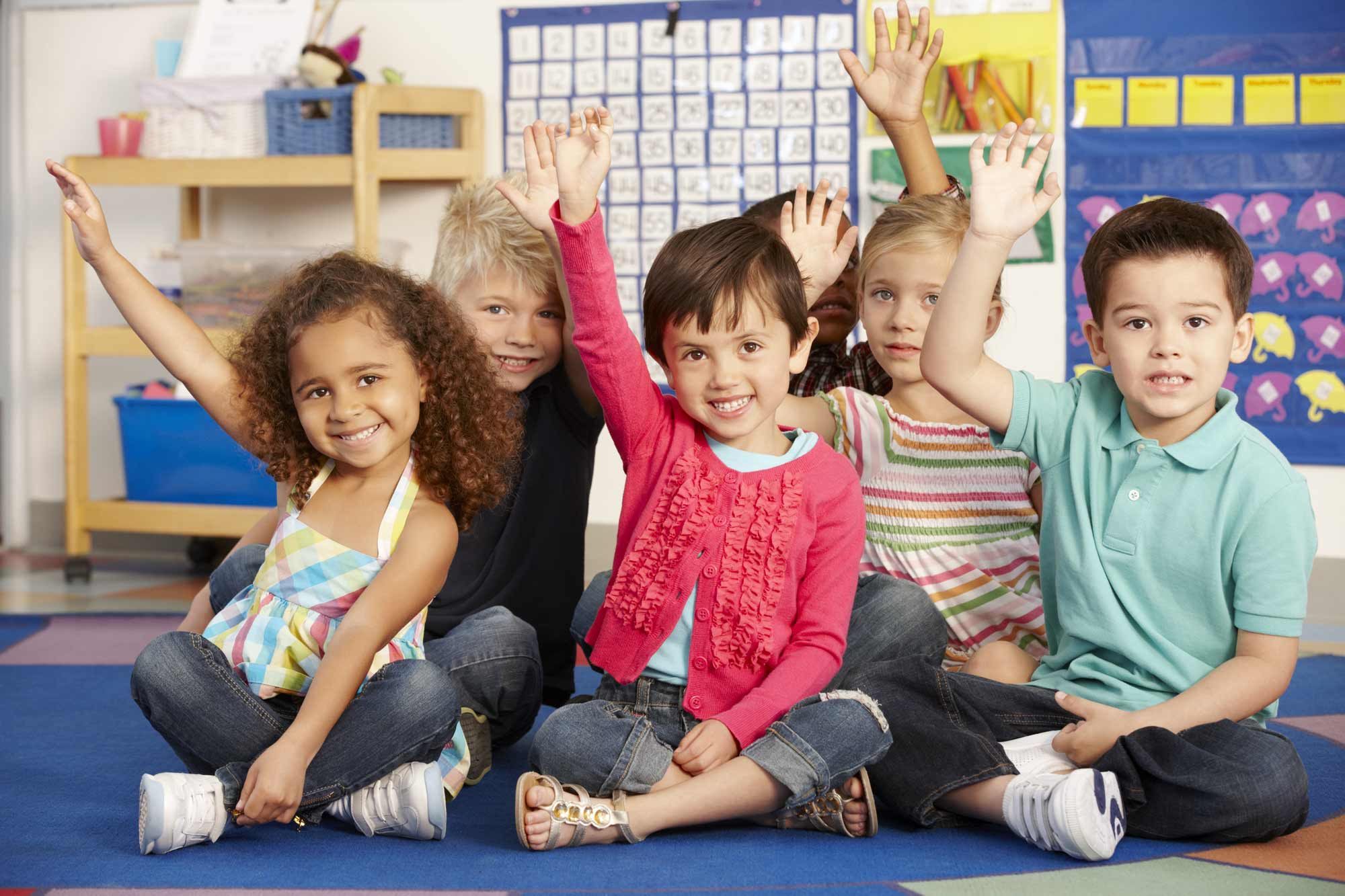 Children in a classroom with their hands raised