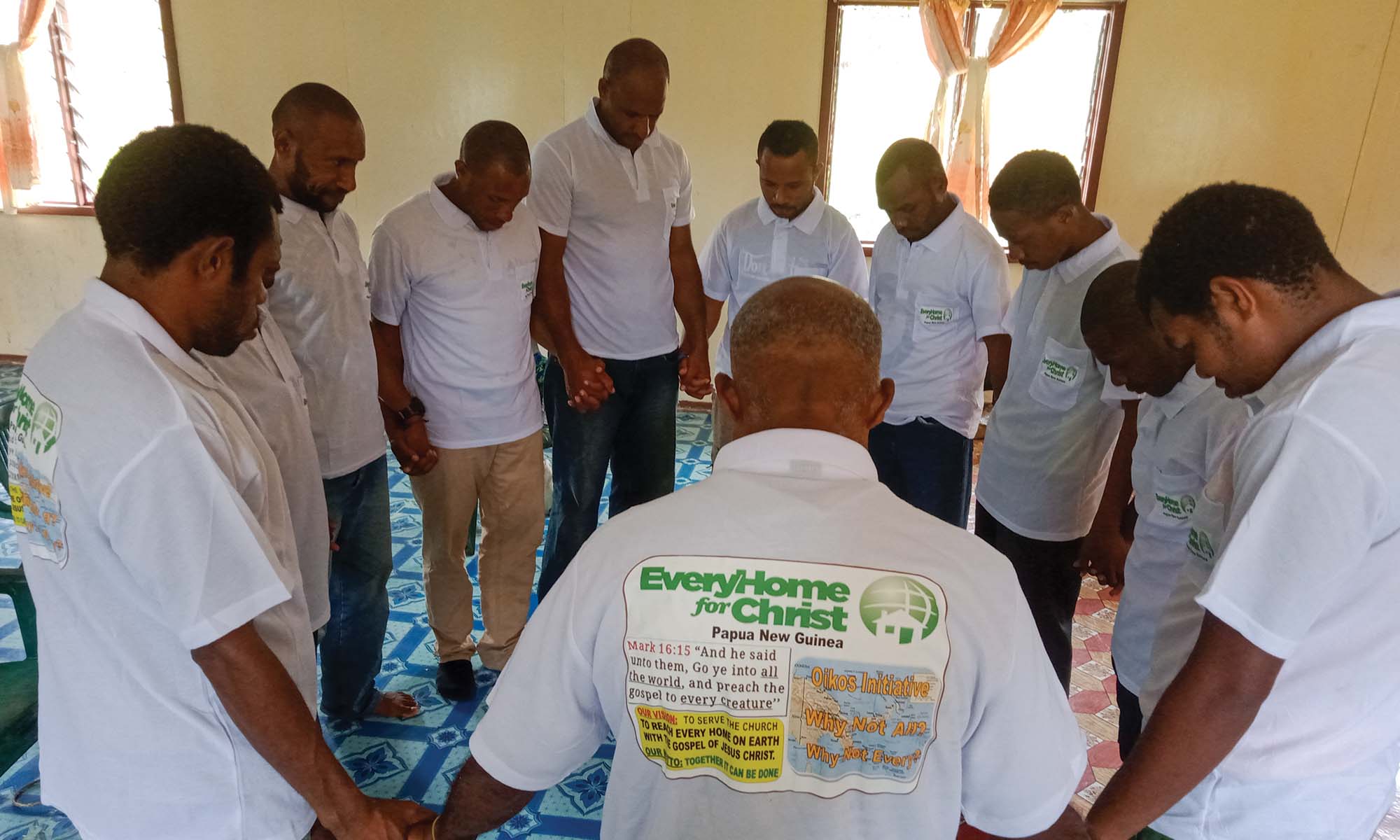 A group of men pray in a circle together