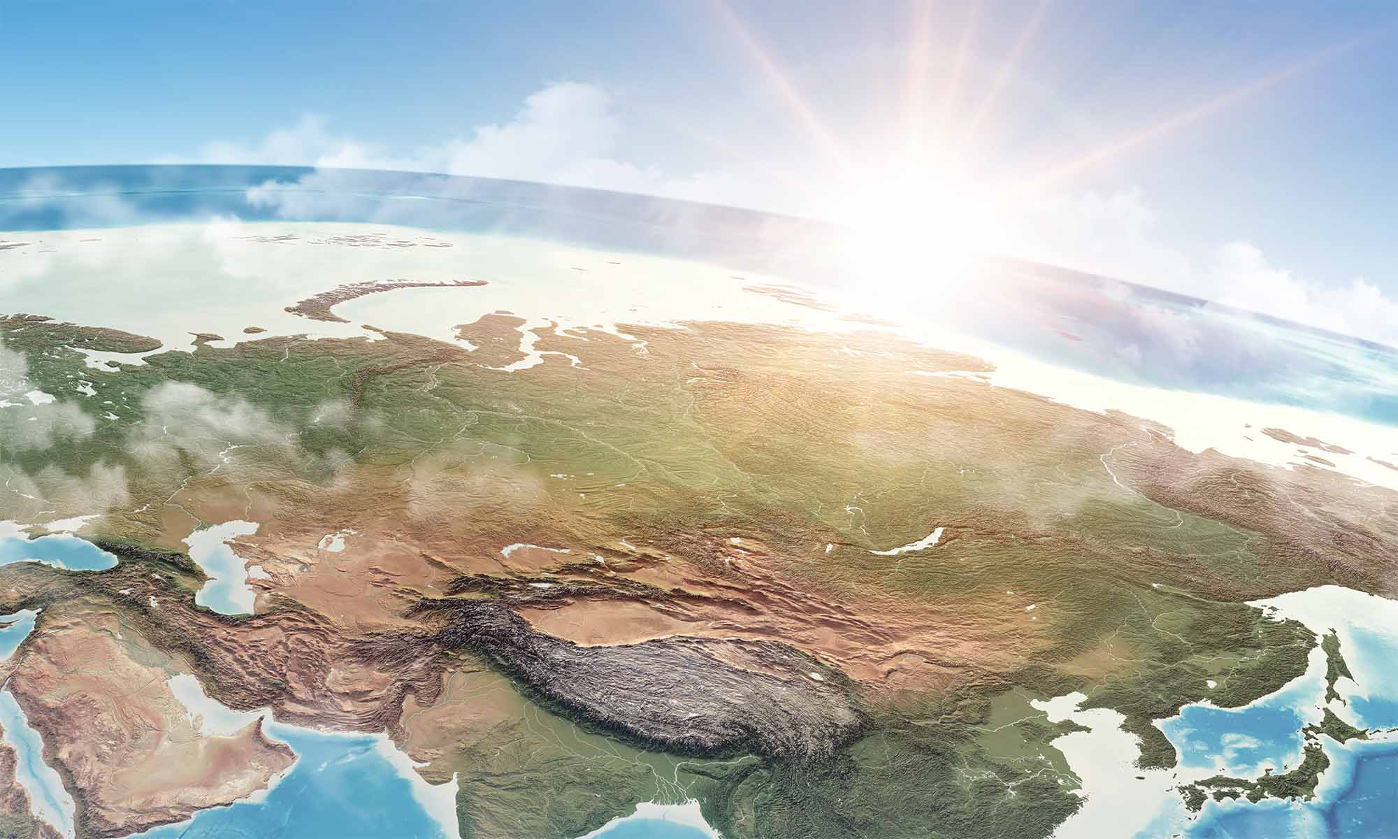 A 3d rendering of the globe as seen from space, with isometric clouds visibly breaking the boundaries of the render and the sun peaking over the earth's horizon.