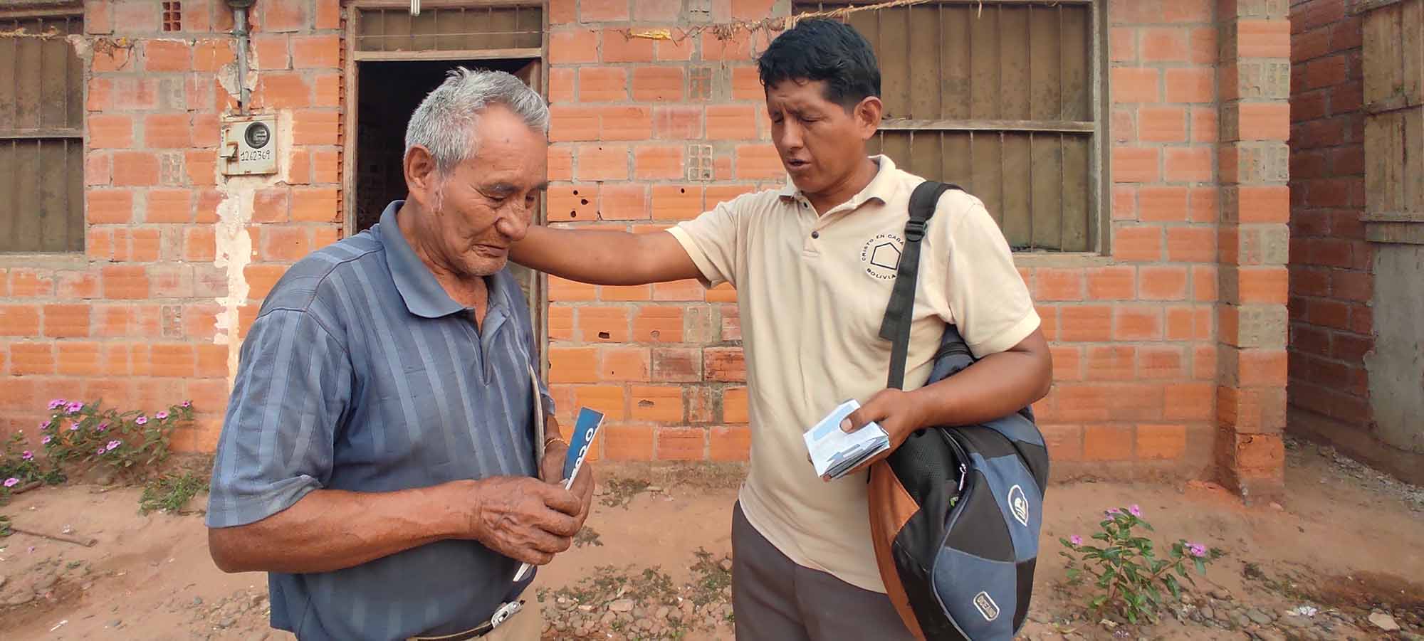 A gospel worker prays for another man in Bolivia.