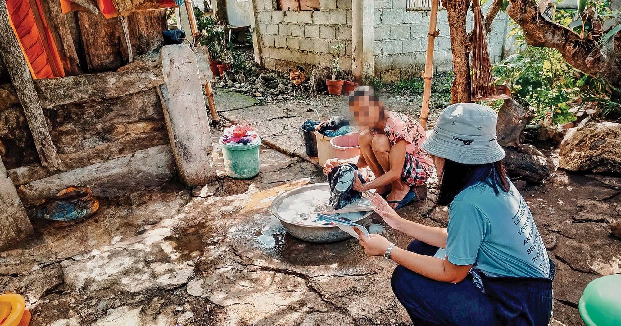 Women in a foreign country bathe clothes in a bucket of water.