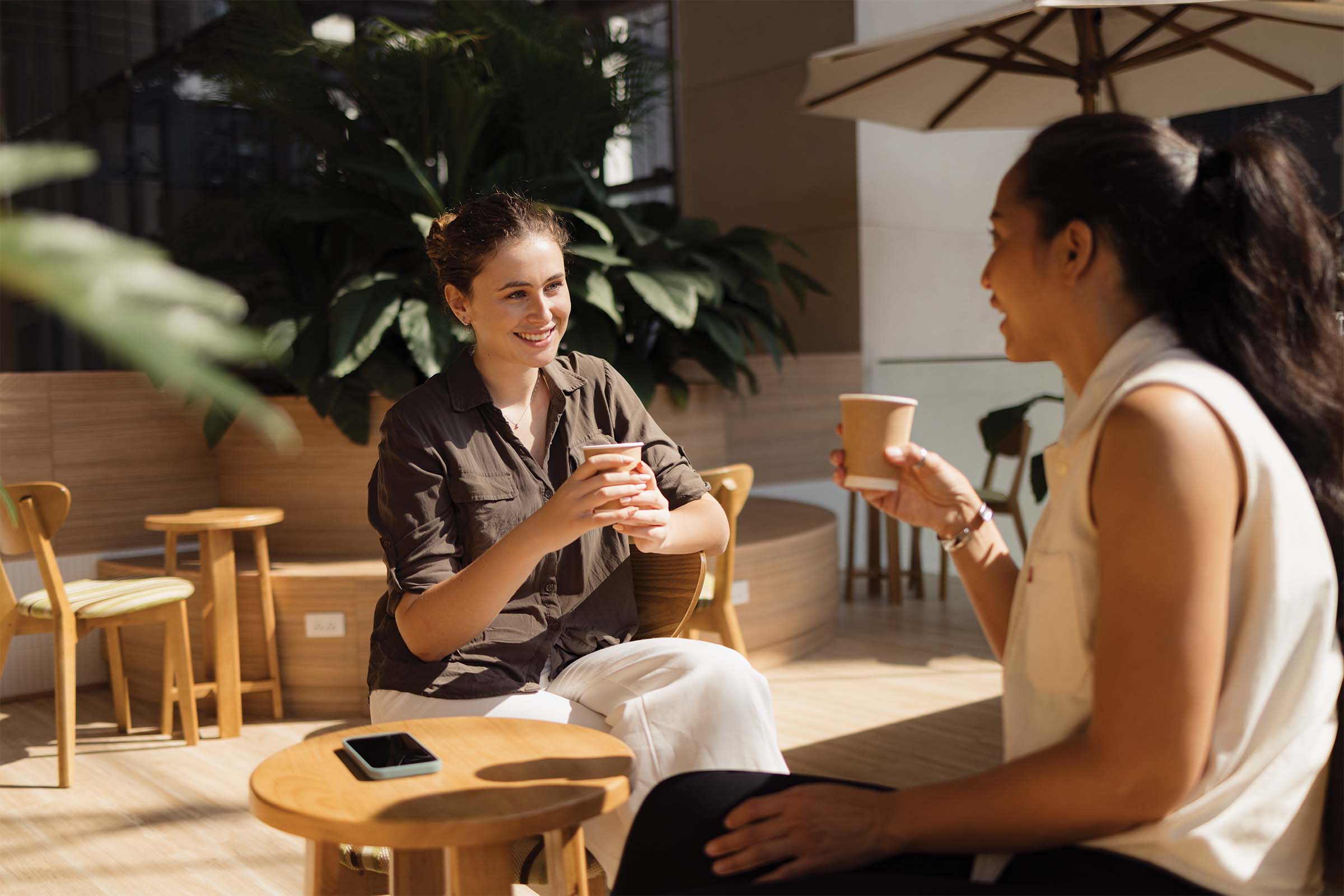 Two women chat over coffee.